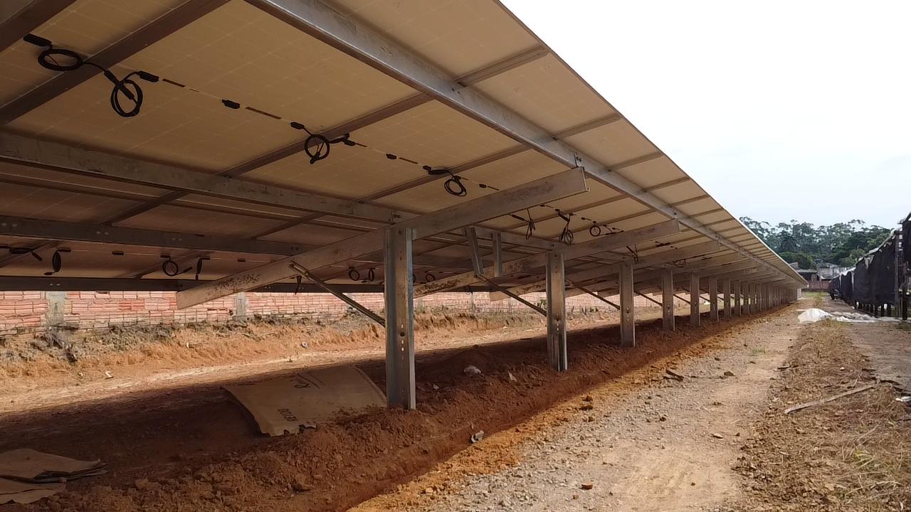 Estrutura metálica de solo sustentando uma longa fileira de painéis solares